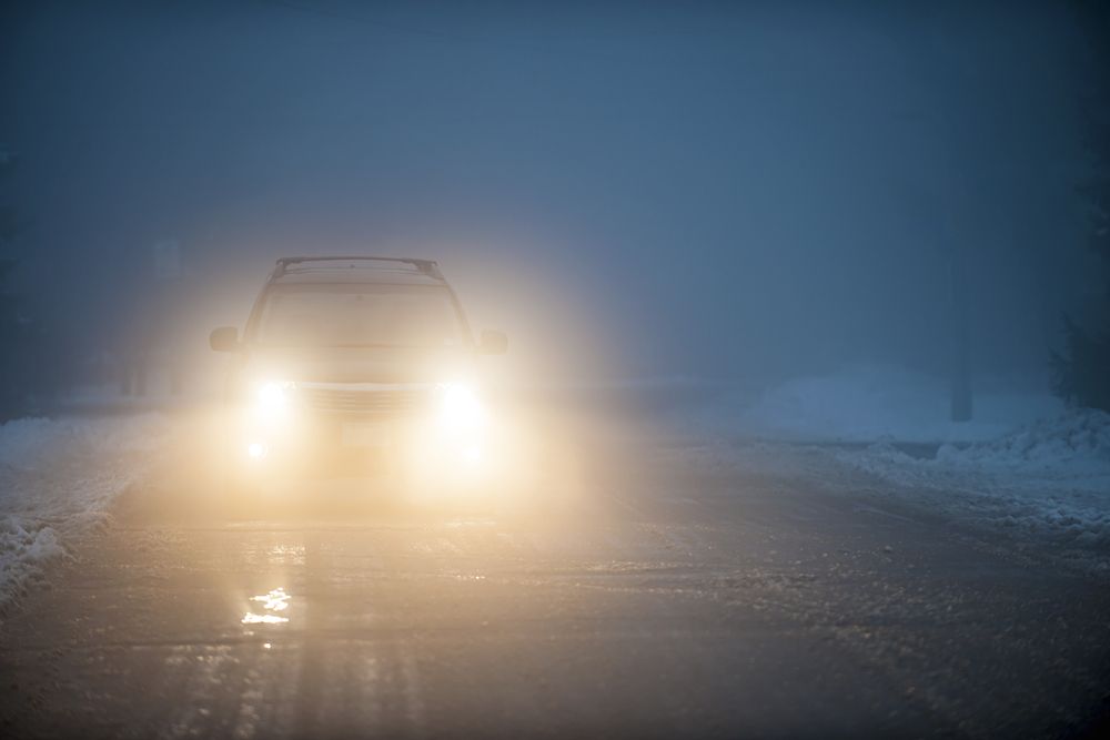 Bright,Headlights,Of,A,Car,Driving,On,Foggy,Winter,Road