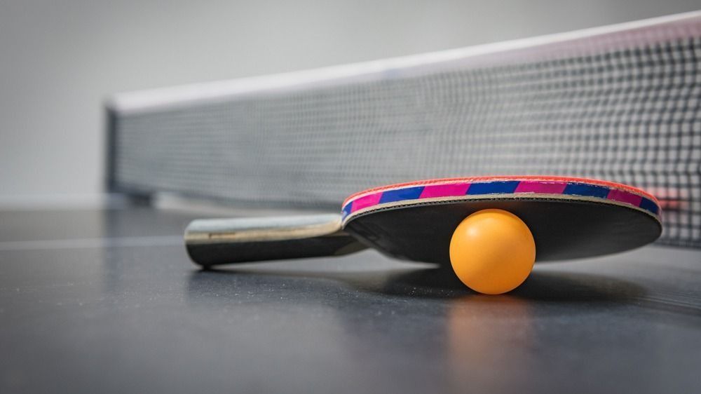 Table,Tennis,Racket,With,Orange,Ball,On,Black,Table