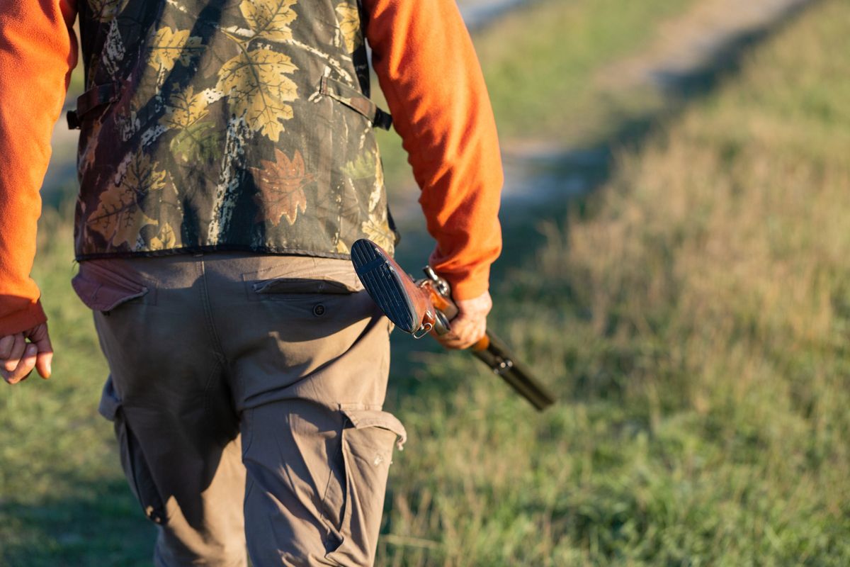 Mature,Hunter,Man,Holding,A,Shotgun,And,Walking,Through,A